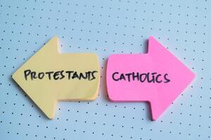 Concept of Protestants or Catholics write on sticky notes isolated on Wooden Table. photo
