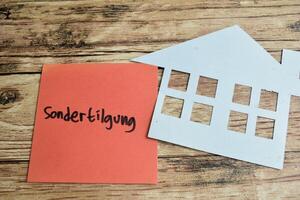 Concept of Learning language - German. Sondertilgung it means Special repayment written on sticky notes. German language isolated on Wooden Table. photo