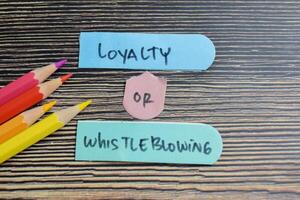 Concept of Loyalty or Whistleblowing write on sticky notes isolated on Wooden Table. photo