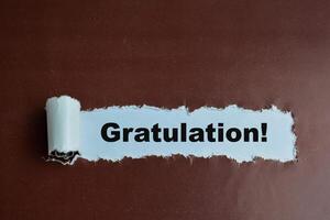 Concept of Learning language - German. Gratulation it means Congratulations written on torn paper. photo