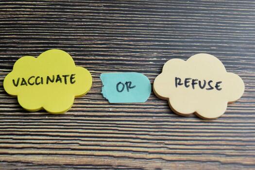 Concept of Vaccinate or Refuse write on sticky notes isolated on Wooden Table. photo