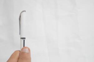 A pen is being held up in front of a white background photo