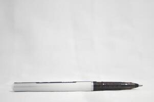 A black pen with a white tip sits on a white surface photo