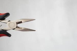 A pair of pliers with a red handle and a black tip photo