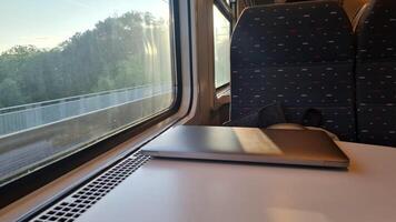 Working on the Go. Using a Laptop on a Train Journey with Scenic Views Outside the Window - Emphasizing Productive Travel and Efficient Transportation photo