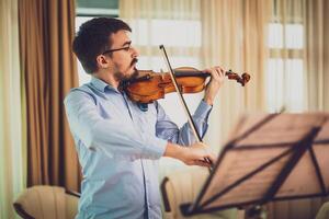 Man playing violin at home. He is practicing for live performance. photo
