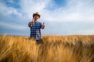 Portrait of happy farmer in his wheat field. He is satisfied with crops. photo
