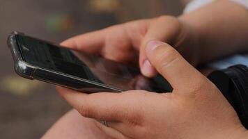 Point finger on screen of mobile phone. Person texting text message, hipster touch smartphone screen. Girl hands holding scrolling chatting working. Summer park. Close up. Copy space. Selective focus video