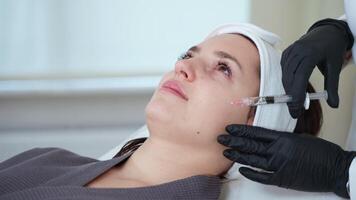 cosmetologist is using injectable filler for rejuvenating face skin of female client video