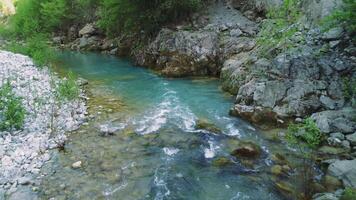 Drone captures rapid, stream in mountainous terrain. Low aerial view of rapid, stream flowing over rocks. Footage shows secluded rapid, stream ideal for adventurers video