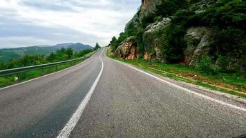 First-person view driving along winding road in mountains. Footage captures journey on narrow winding road. Camera follows winding road through scenic terrain video