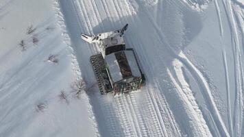 Snowcat vehicle clearing a path in snowy terrain, seen from an aerial perspective video