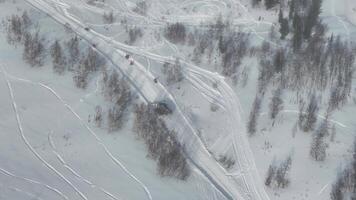 A drone captured an aerial view of a snowy road with ski tracks and people in a winter landscape video