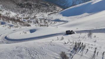 A snowplow is clearing a snowy mountain road in an aerial view during a winter day video