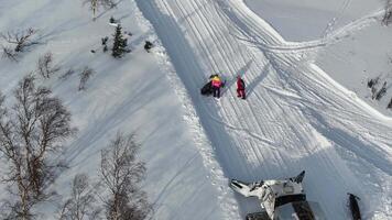 Snowmobiles riding through a beautiful snowy trail observed from a birds eye view video