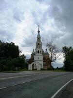 a church on the side of the road with a cloudy sky photo