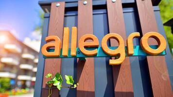 Warsaw, Poland. 8 June 2024. View of the Allegro Group logotype on the wooden wall with ivy. A modern residential building in the background. photo