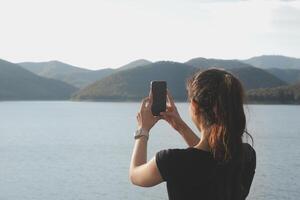 Young woman traveler in casual clothes with backpack from back on background of beautiful view on mountains photo
