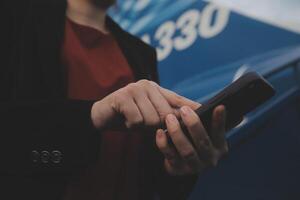 Young asian woman in international airport, using mobile smartphone and checking flight at the flight information board photo