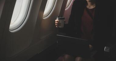 Blonde female tourist checking incoming notification on smartphone sitting on seat of airplane with netbook.Young businesswoman share media from telephone on laptop computer during plane flight photo
