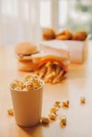 A bucket of popcorn, top-view, warm colors, light brown wooden background, flat lay, daylight macro close-up photo