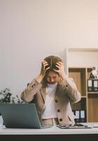 Asian women sitting in an office With stress and eye strain Tired, portrait of sad unhappy tired frustrated disappointed lady suffering from migraine sitting at the table, Sick worker concept photo