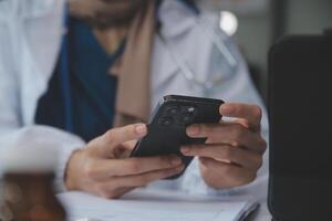 Consultation Online. Unrecognizable doctor using smartphone at workplace, messaging with patient, prescribing treatment photo