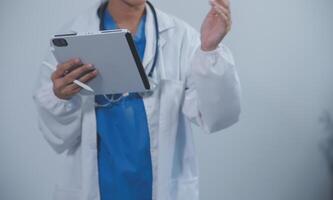 Woman doctor using tablet computer while standing straight in hospital photo