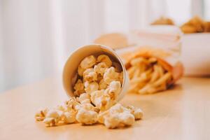 A bucket of popcorn, top-view, warm colors, light brown wooden background, flat lay, daylight macro close-up photo