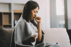 Upset woman frustrated by problem with work or relationships, sitting on couch, embracing knees, covered face in hand, feeling despair and anxiety, loneliness, having psychological trouble photo