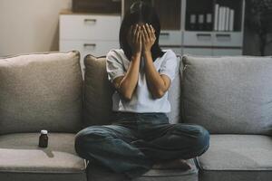 Upset woman frustrated by problem with work or relationships, sitting on couch, embracing knees, covered face in hand, feeling despair and anxiety, loneliness, having psychological trouble photo