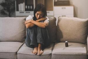 Upset woman frustrated by problem with work or relationships, sitting on couch, embracing knees, covered face in hand, feeling despair and anxiety, loneliness, having psychological trouble photo