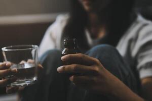 Upset woman frustrated by problem with work or relationships, sitting on couch, embracing knees, covered face in hand, feeling despair and anxiety, loneliness, having psychological trouble photo