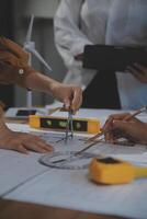 Team of multiethnic architects working on construction plans in meeting room. Engineers discussing on project in office. Mature businessman and woman standing around table working on blueprint. photo