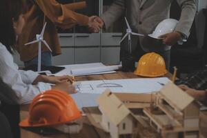 Construction team shake hands greeting start new project plan behind yellow helmet on desk in office center to consults about their building project. in sun light photo