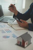 Businessmen holding pens, signing home titles with insurance, care about real estate services and the idea of real estate agents offering interest in installments to their customers. photo