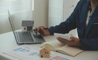 Businessmen holding pens, signing home titles with insurance, care about real estate services and the idea of real estate agents offering interest in installments to their customers. photo