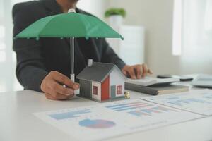 Businessmen holding pens, signing home titles with insurance, care about real estate services and the idea of real estate agents offering interest in installments to their customers. photo