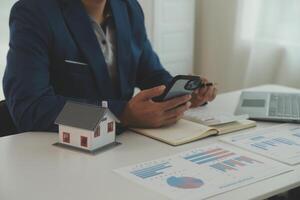Businessmen holding pens, signing home titles with insurance, care about real estate services and the idea of real estate agents offering interest in installments to their customers. photo