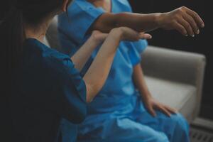 Old woman training with physiotherapist using dumbbells at home. Therapist assisting senior woman with exercises in nursing home. Elderly patient using dumbbells with outstretched arms. photo