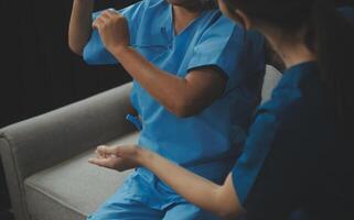 Old woman training with physiotherapist using dumbbells at home. Therapist assisting senior woman with exercises in nursing home. Elderly patient using dumbbells with outstretched arms. photo