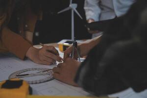 Team of multiethnic architects working on construction plans in meeting room. Engineers discussing on project in office. Mature businessman and woman standing around table working on blueprint. photo