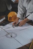 Team of multiethnic architects working on construction plans in meeting room. Engineers discussing on project in office. Mature businessman and woman standing around table working on blueprint. photo