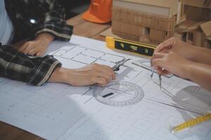 Team of multiethnic architects working on construction plans in meeting room. Engineers discussing on project in office. Mature businessman and woman standing around table working on blueprint. photo