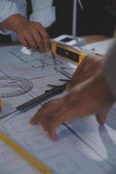 Team of multiethnic architects working on construction plans in meeting room. Engineers discussing on project in office. Mature businessman and woman standing around table working on blueprint. photo