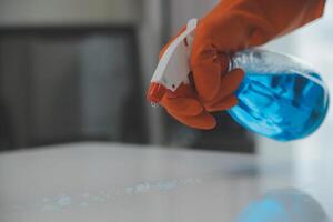Woman cleaning table using rag and diffuser at home. photo