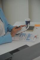 Charming Young asian businesswoman sitting on laptop computer in the office, making report calculating balance Internal Revenue Service checking document. photo