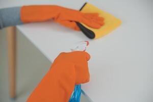 Woman cleaning table using rag and diffuser at home. photo