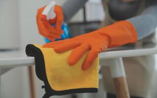 Woman cleaning table using rag and diffuser at home. photo