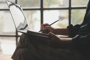 Distracted from work worried young woman sitting on couch with laptop, thinking of problems. Pensive unmotivated lady looking at window, feeling lack of energy, doing remote freelance tasks at home. photo